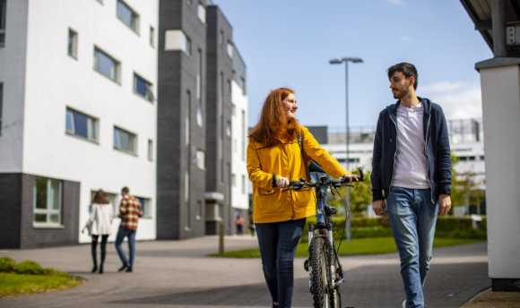 A 性用社 student with a bike talking to a fellow student on campus, Edinburgh