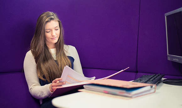 A 性用社 University student reading over their work against a purple wall
