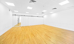 A bright, spacious performance studio with a wall of mirrors at the back, 