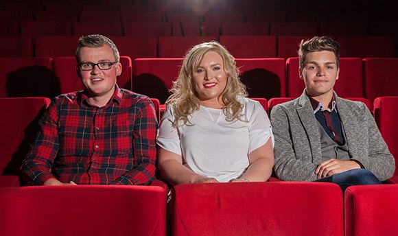 Three  University students sitting in plush red seats at the theatre
