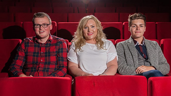 Three  University students sitting in plush red seats at the theatre