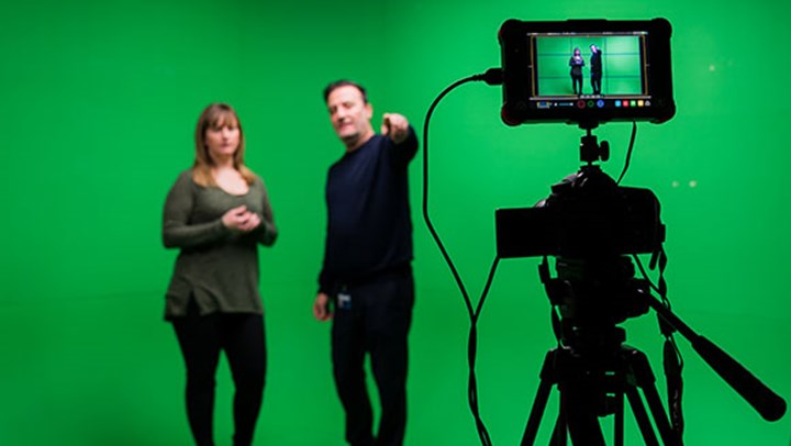 A  University student being briefed in front of a green screen