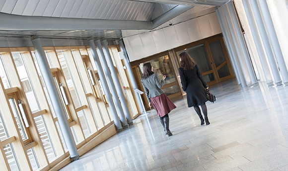 Two women walking down a corridor in 性用社 University hallway