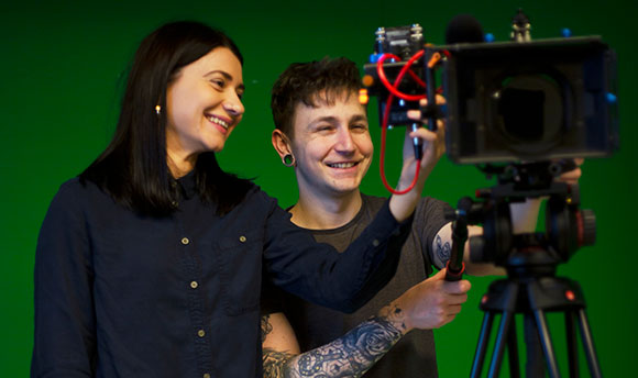 Two  students with a professional camera in front of a green screen