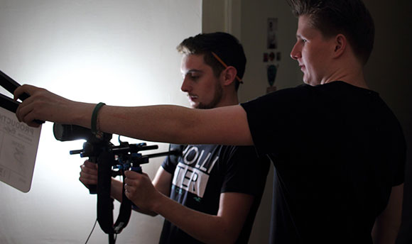 Two  students, one setting up a camera and the other holding the clapper board in front of the lens