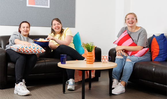 Three female students enjoy popcorn while watching a film in their  Student Accommodation