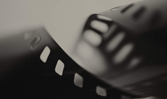 A blurred black photo of a old fashioned film reel.